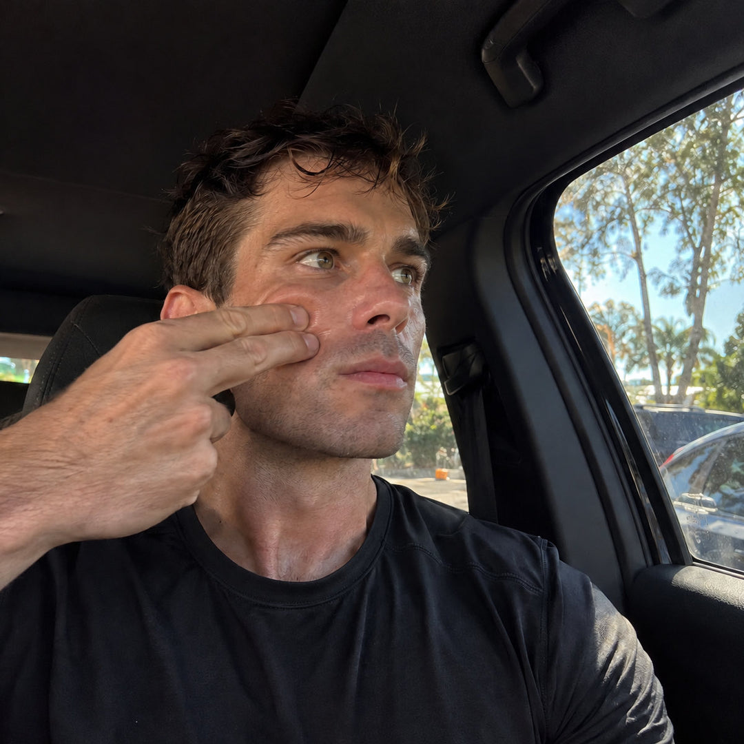 Two fingers pulling the cheek out and away from the nose, in a parked car.